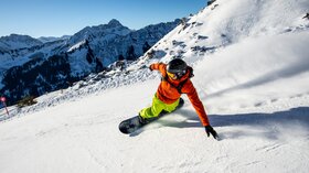Snowboarder fährt einen verschneiten Hang hinunter. © Sport Kessler GmbH